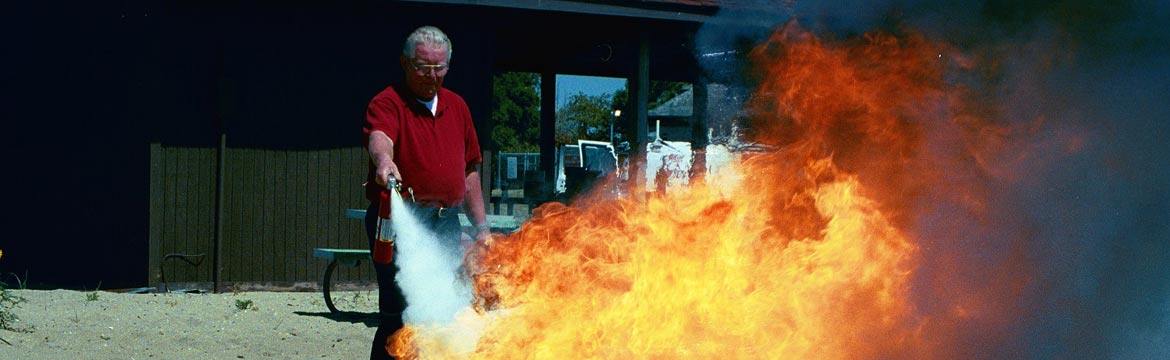 A man tries to put out a fire with a small extinguisher