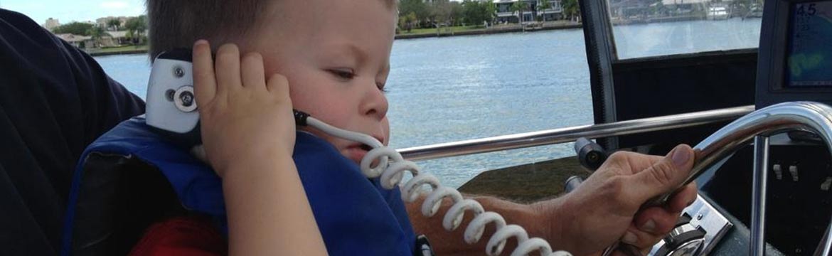 a young boy talks on a boat radio