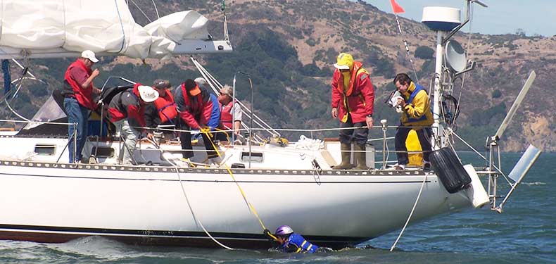 crew assisting a man overboard during a crew overboard drill