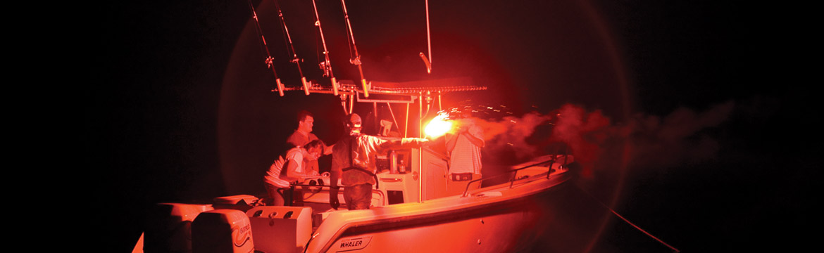 men test a red flare on a boat at night