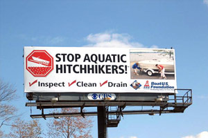 A highway billboard reads, Stop Aquatic Hitchhikers