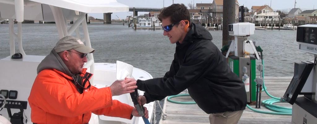 a man fueling up his boat on the water at a gas dock