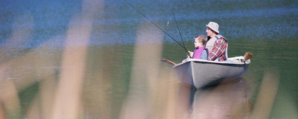 A father and son fish from a row boat.